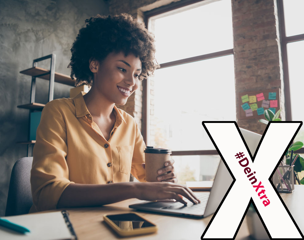 #DeinXtra | Bild zeigt eine lächelnde Frau am Laptop mit To-Go-Becher in der Hand. |  © AdobeStock: deagreez